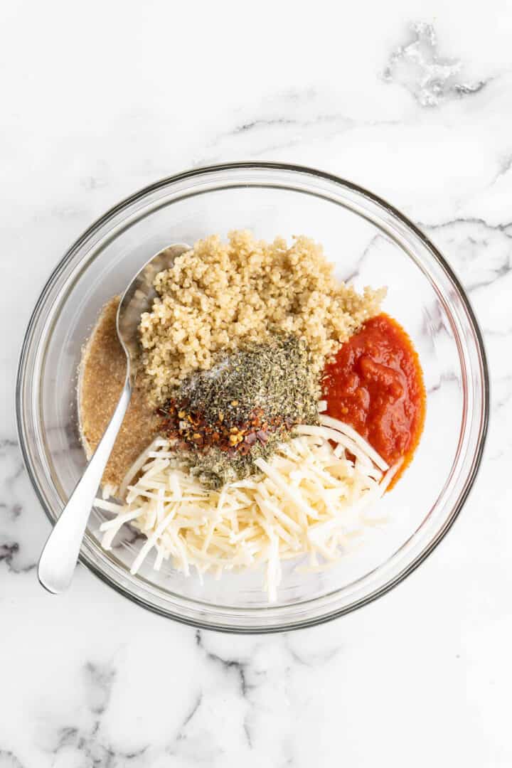 Overhead view of quinoa pizza bite ingredients in glass mixing bowl
