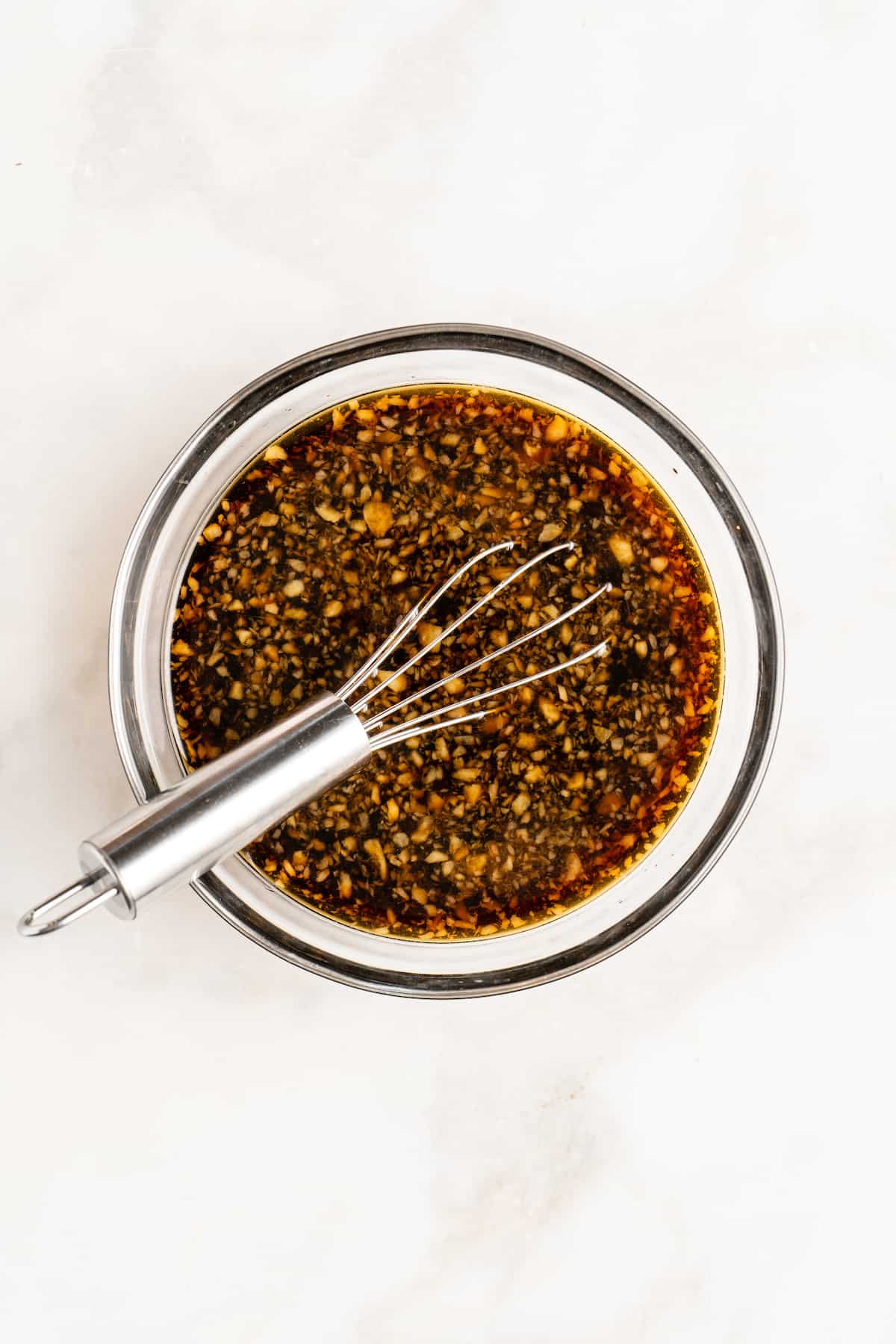 Overhead view of stir fry sauce in glass bowl with whisk