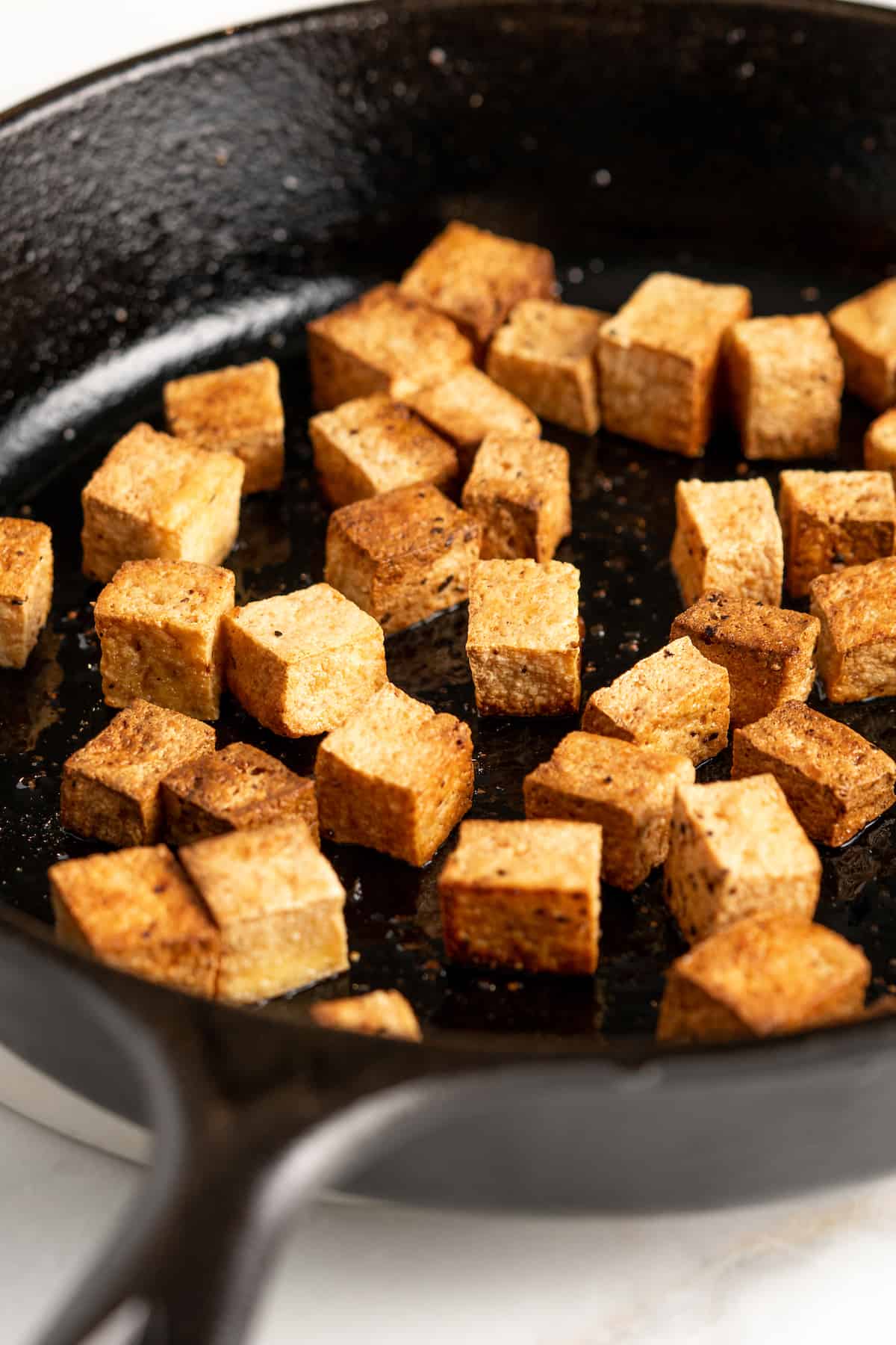 Cooked tofu cubes in cast iron skillet