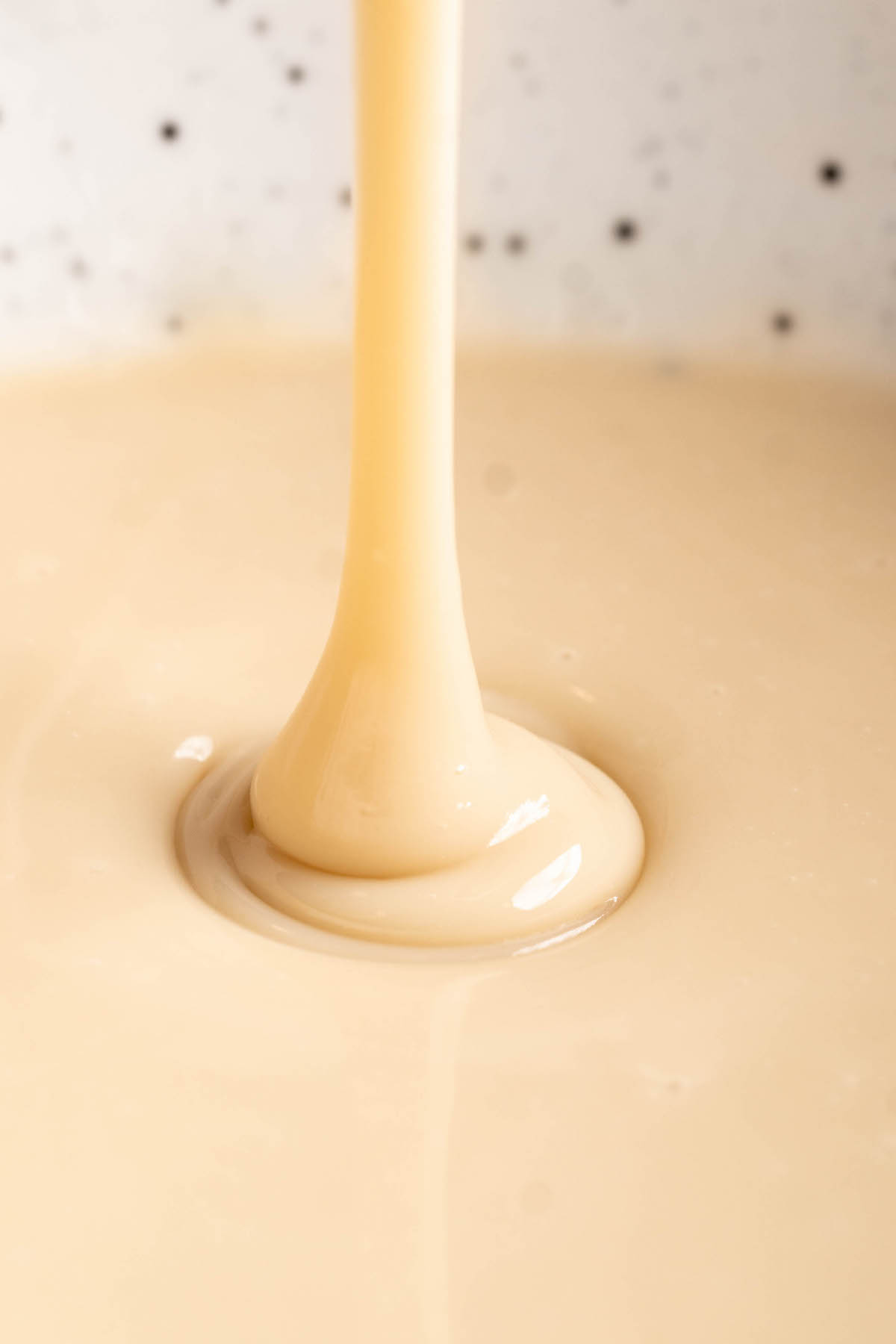 Closeup showing thickness of vegan condensed milk being drizzled into bowl
