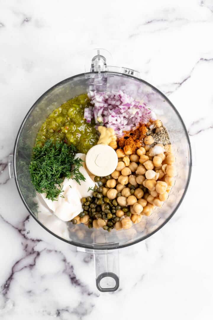 In just 15 minutes, you can make a creamy, flavourful chickpea tuna salad to layer onto sandwiches or include in your meal prep lunches! Overhead view of vegan tuna ingredients in food processor bowl