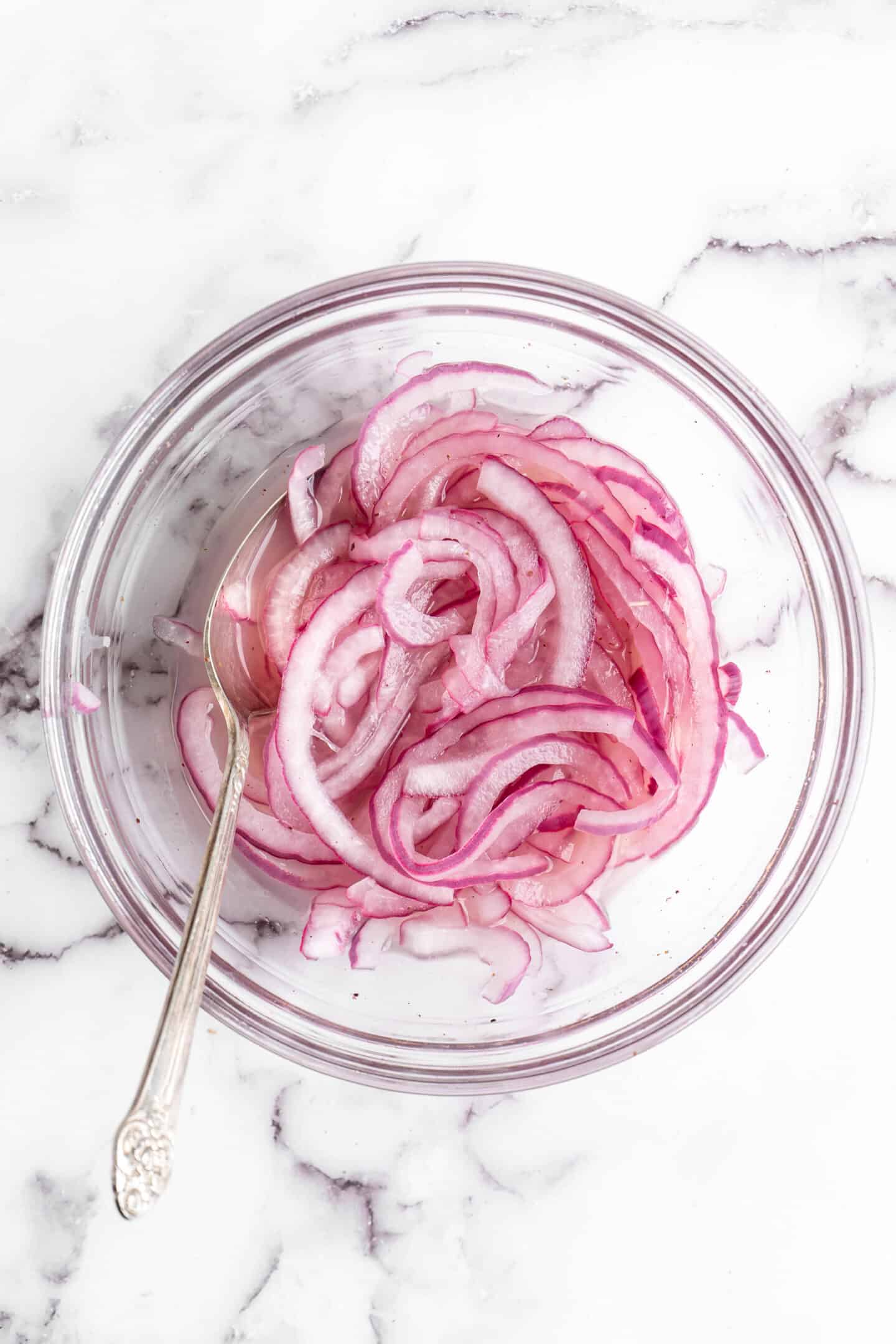 Quick pickled onions in glass bowl with spoon