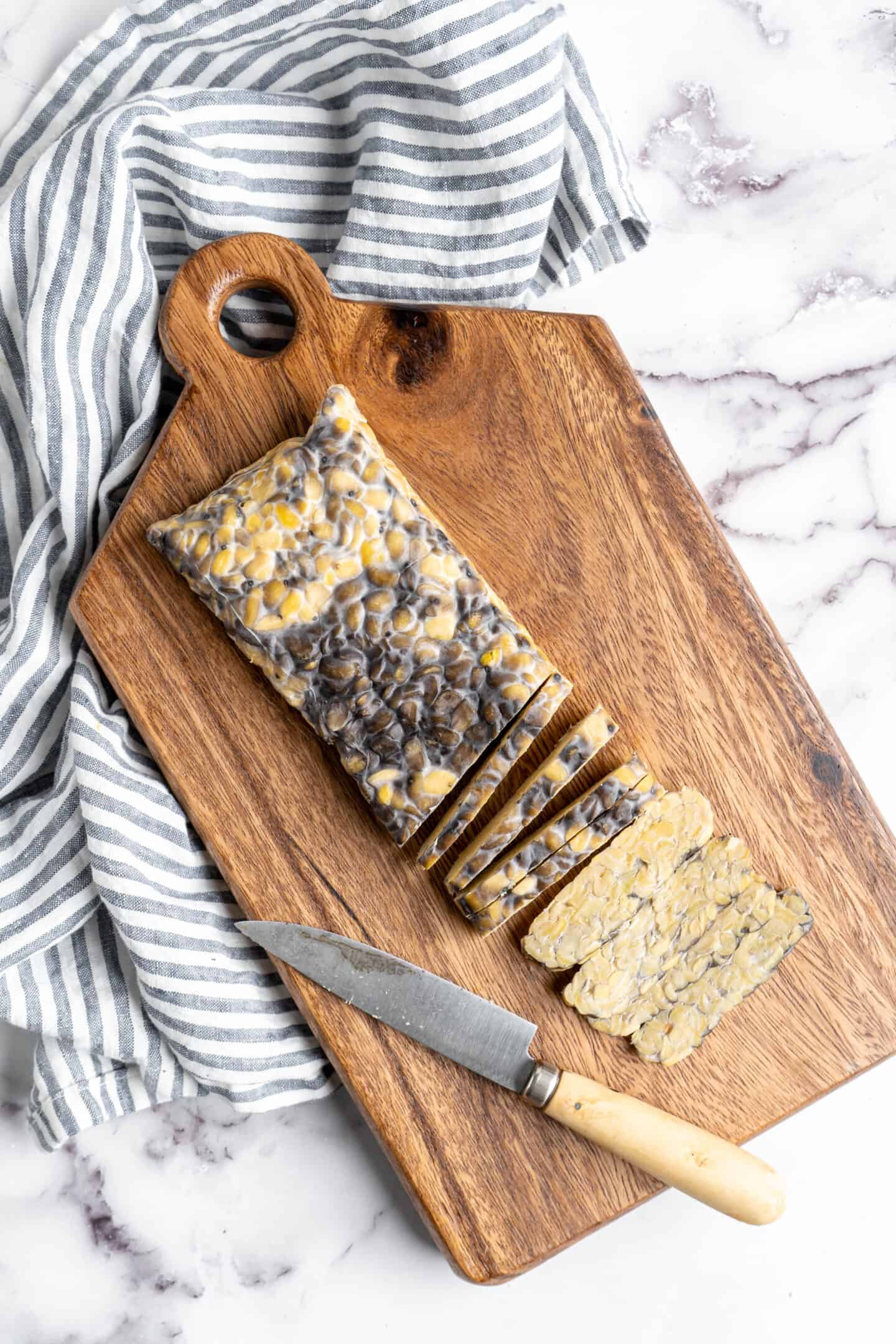 Slicing slab of tempeh on cutting board