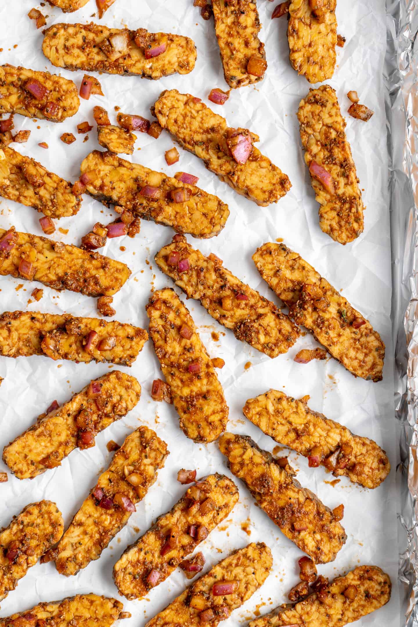 Vegan tempeh gyros strips on parchment-lined baking sheet