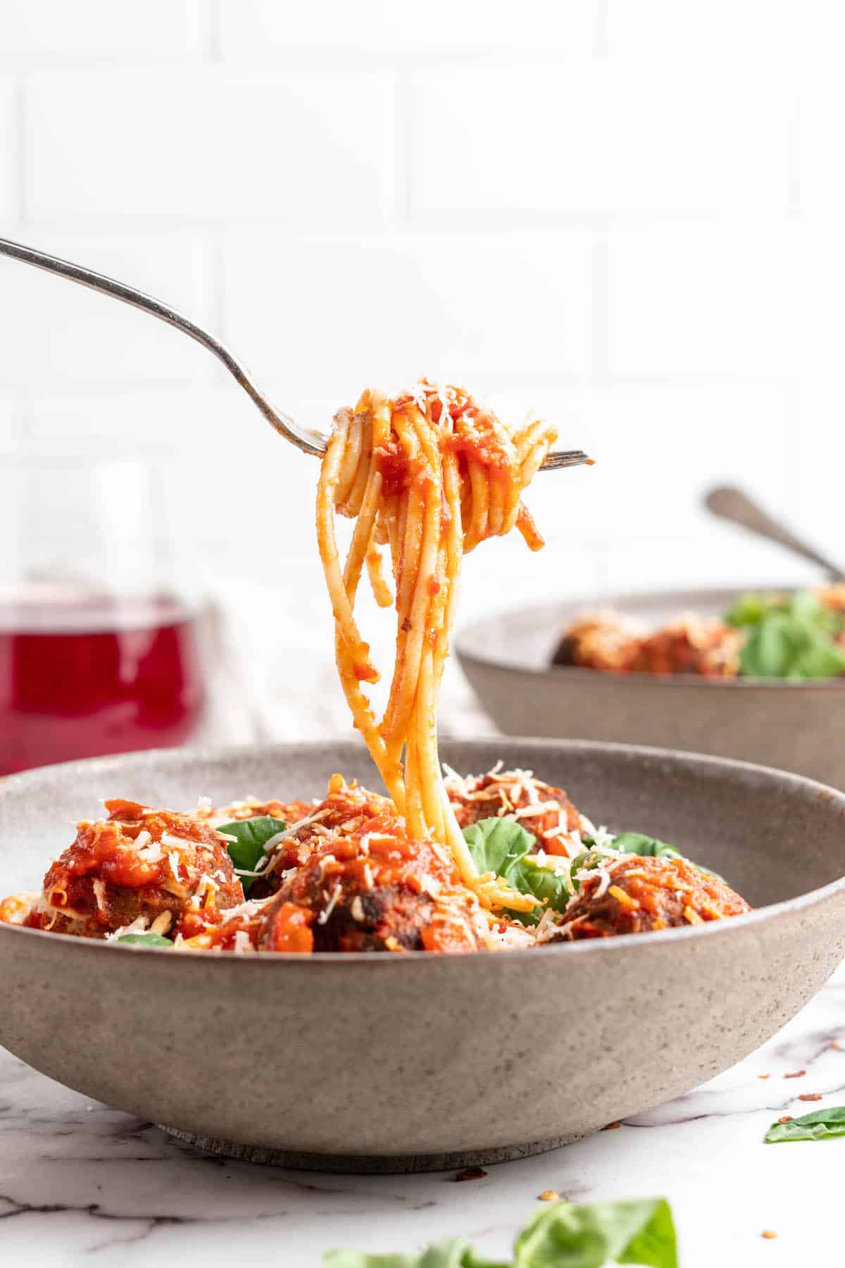 Spaghetti on fork held over bowl of vegan spaghetti and meatballs