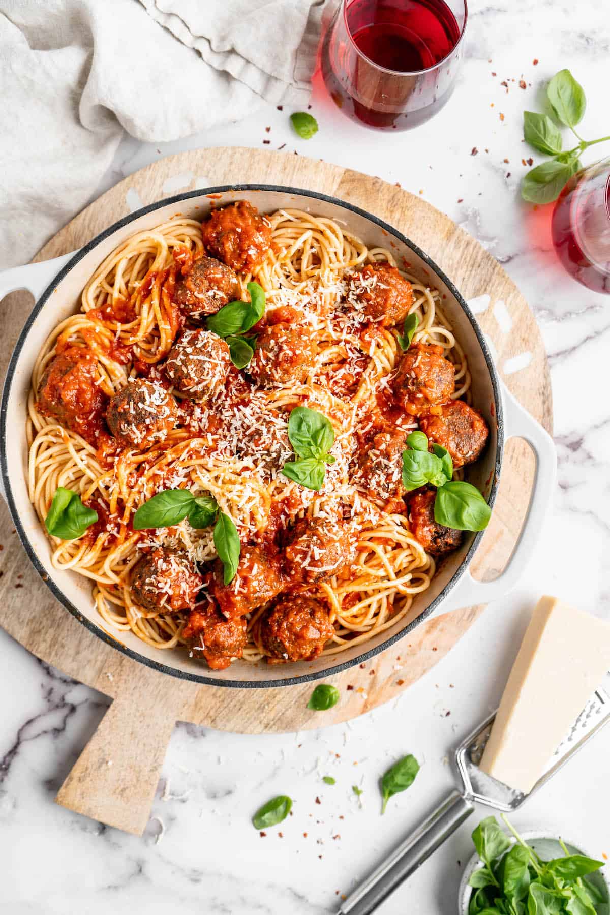 Pan of vegan spaghetti and meatballs set on wood board