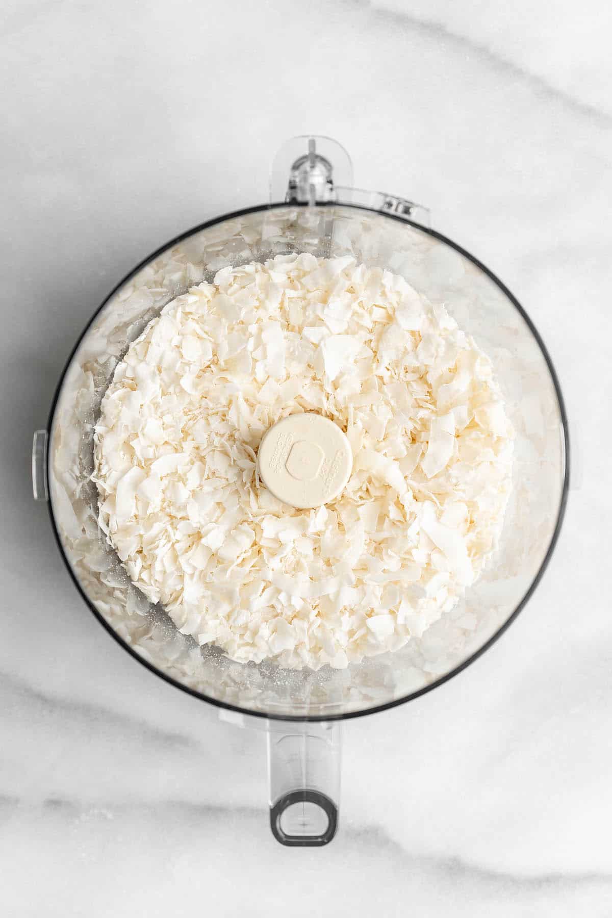 Overhead view of coconut flakes in food processor bowl