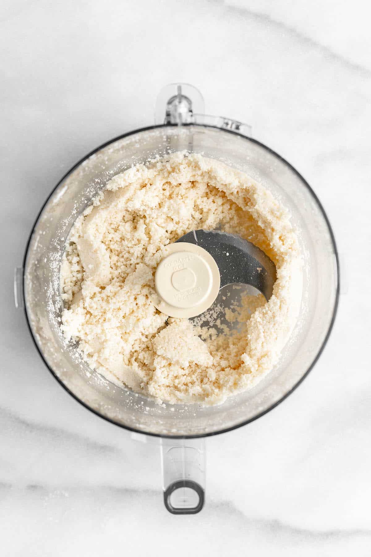 Overhead view of coconut flakes in food processor bowl after processing