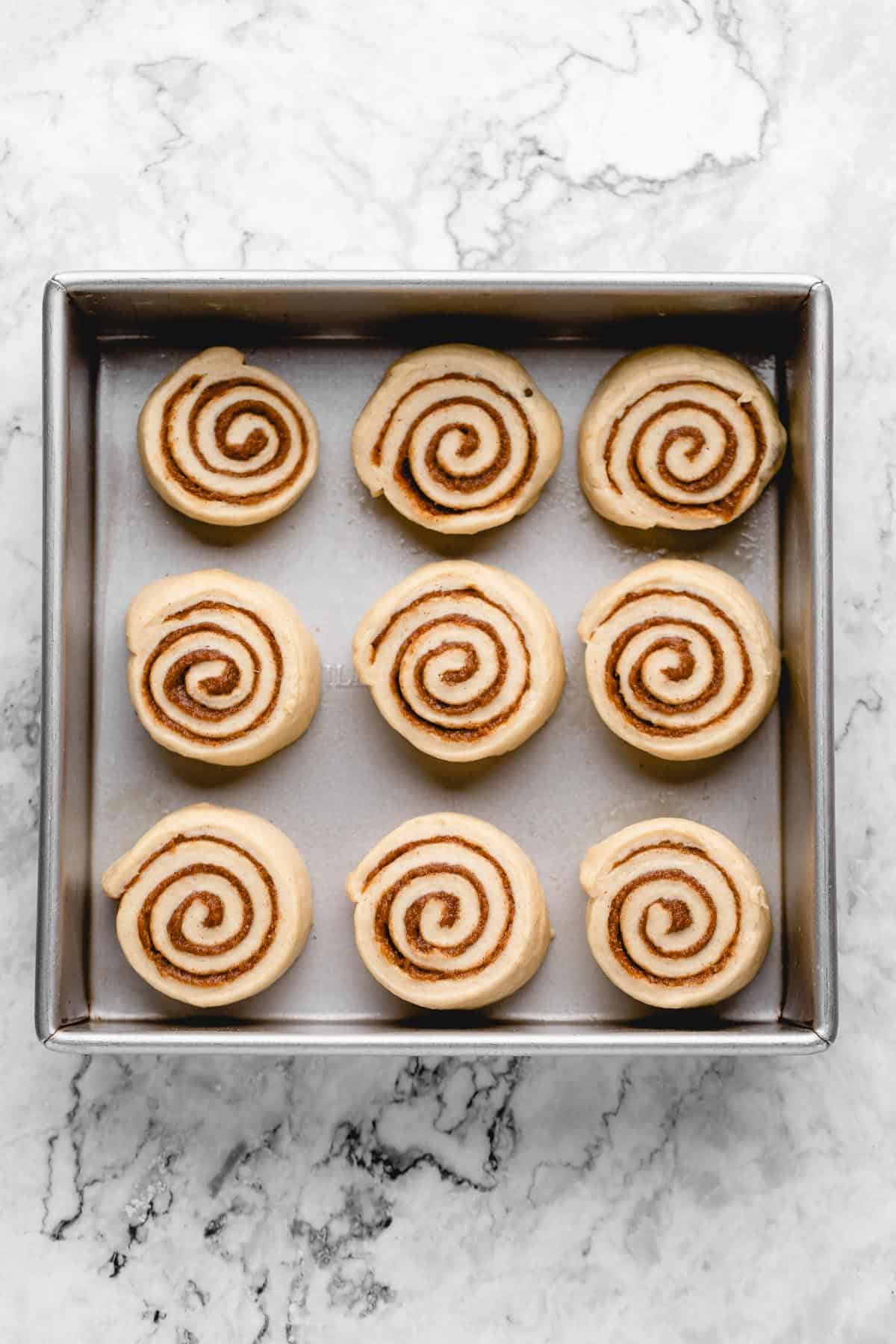 Overhead view of cinnamon rolls in pan before second rise