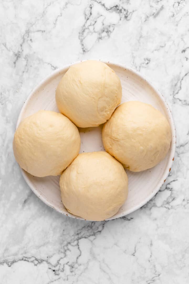 Four balls of bread dough on plate