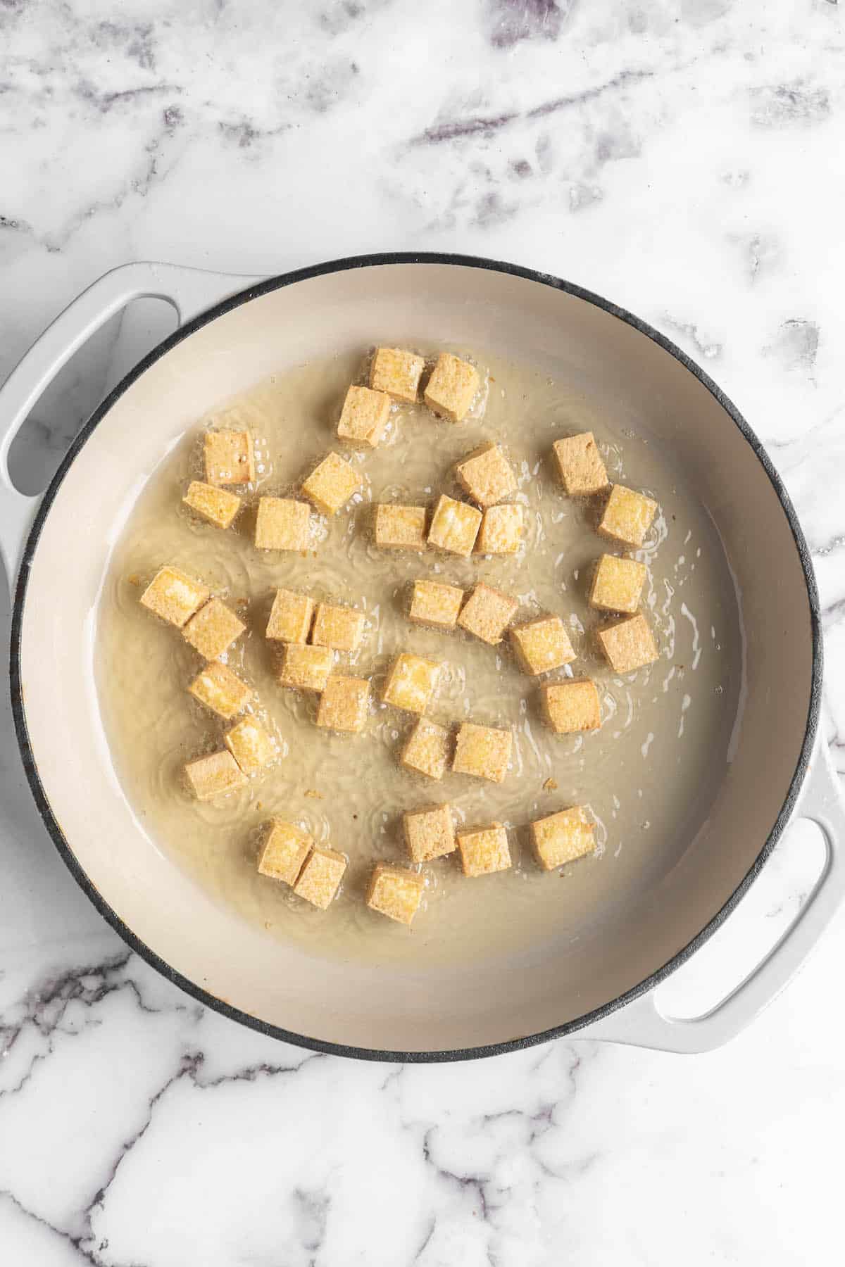 Overhead view of tofu cubes in skillet with oil