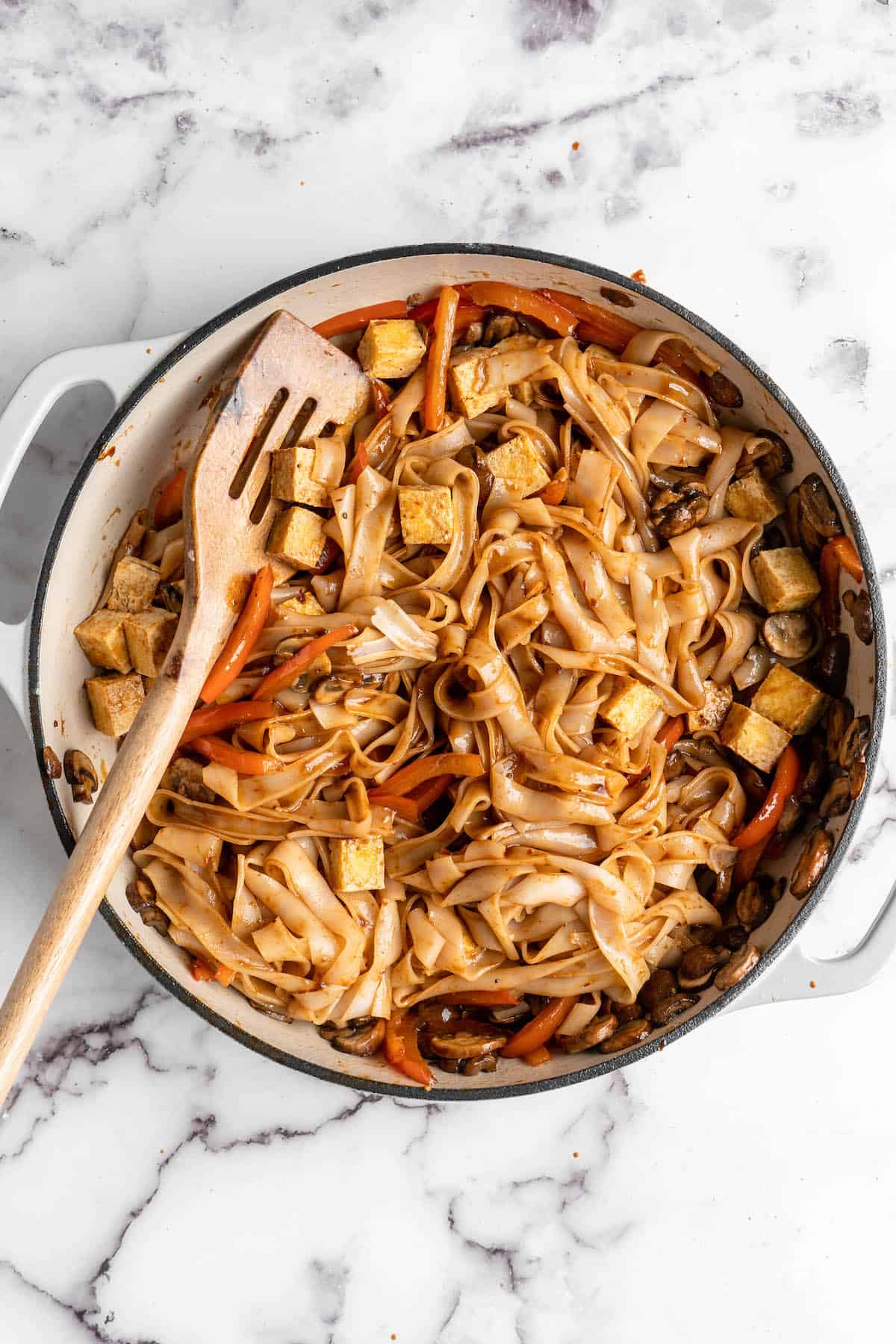Overhead view of vegan Pad Thai in skillet after adding noodles and sauce