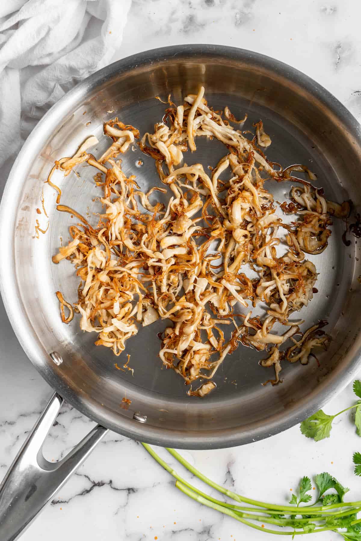 Overhead view of shredded oyster mushrooms in skillet
