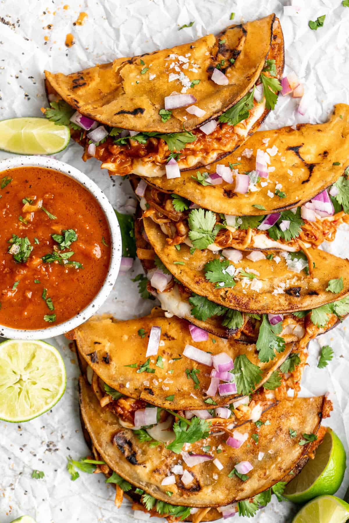 Overhead view of vegan birria tacos with a bowl of birria sauce.