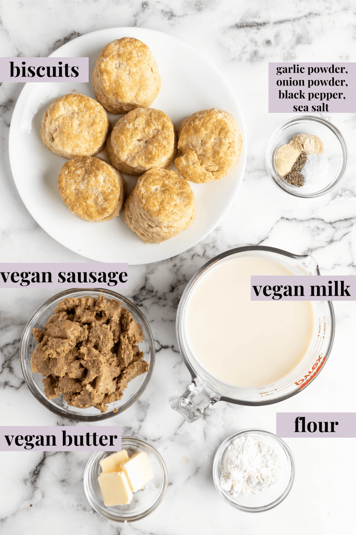 Overhead view of the labeled ingredients for vegan biscuits and gravy: biscuits, vegan sausage, vegan milk, vegan butter, flour, garlic powder, onion powder, salt, and pepper