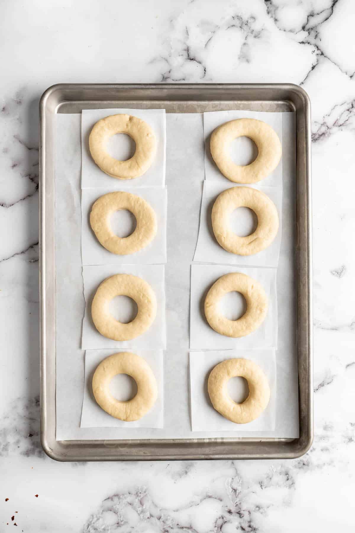 Uncooked donuts on a tray with parchment paper
