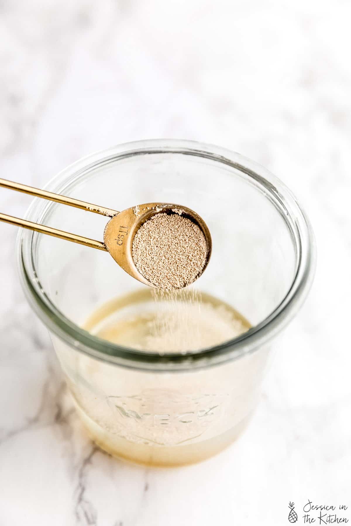 A spoon pouring yeast into water