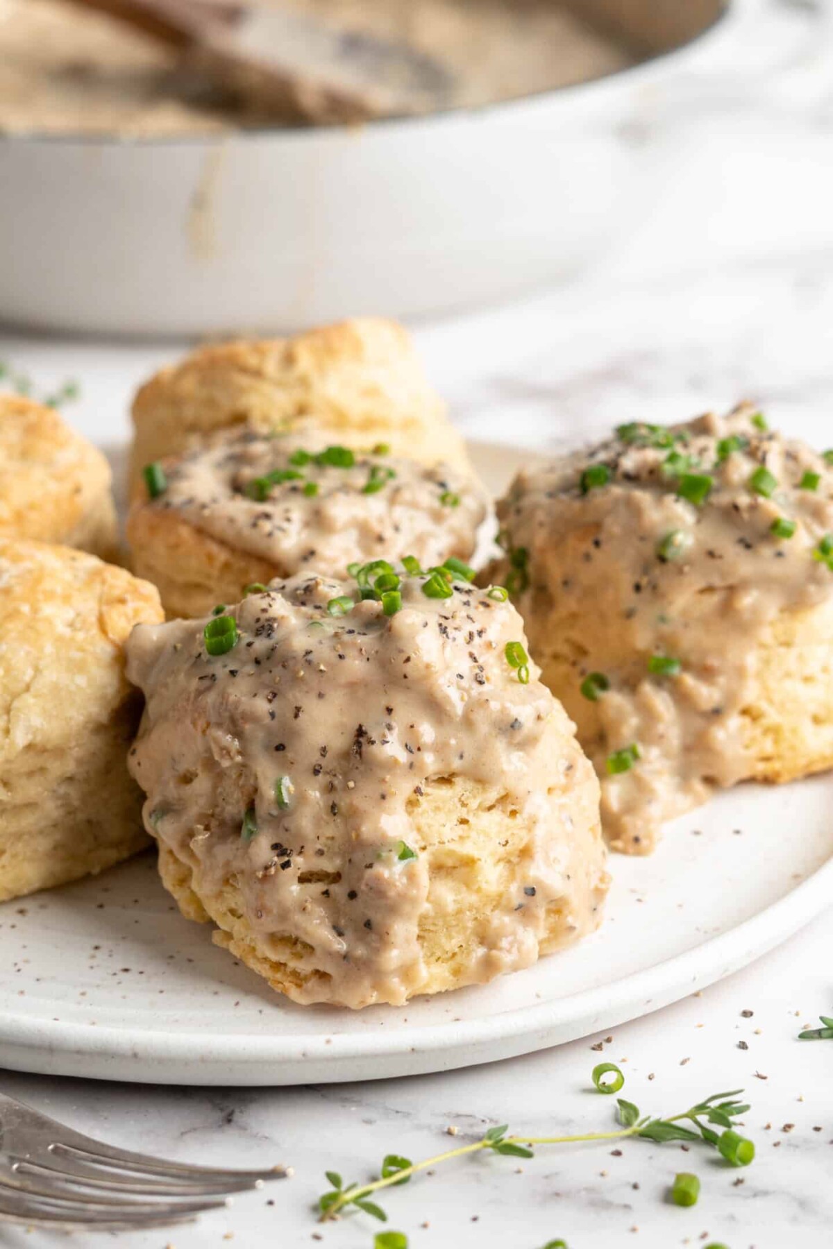 A plate with a few biscuits and gravy on it, garnished with chives