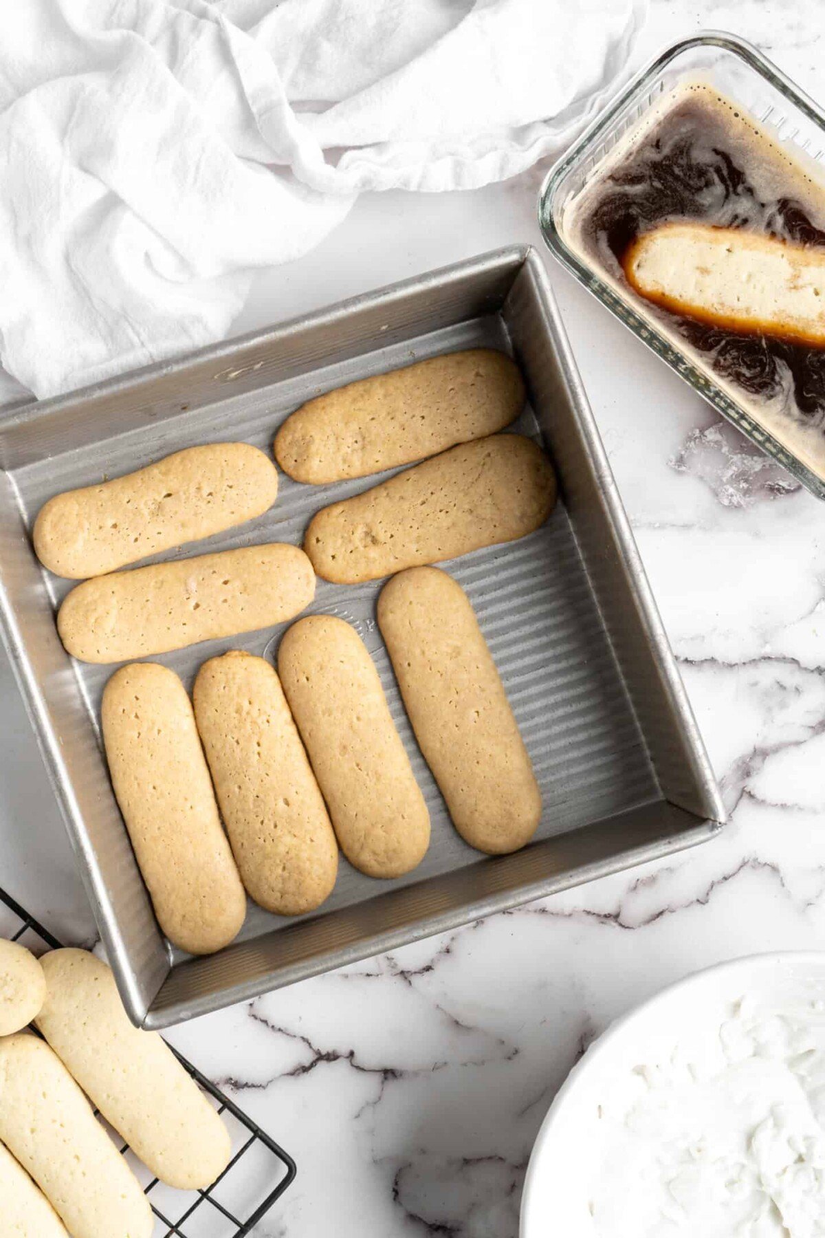 A baking dish with eight ladyfingers placed in a layer in it