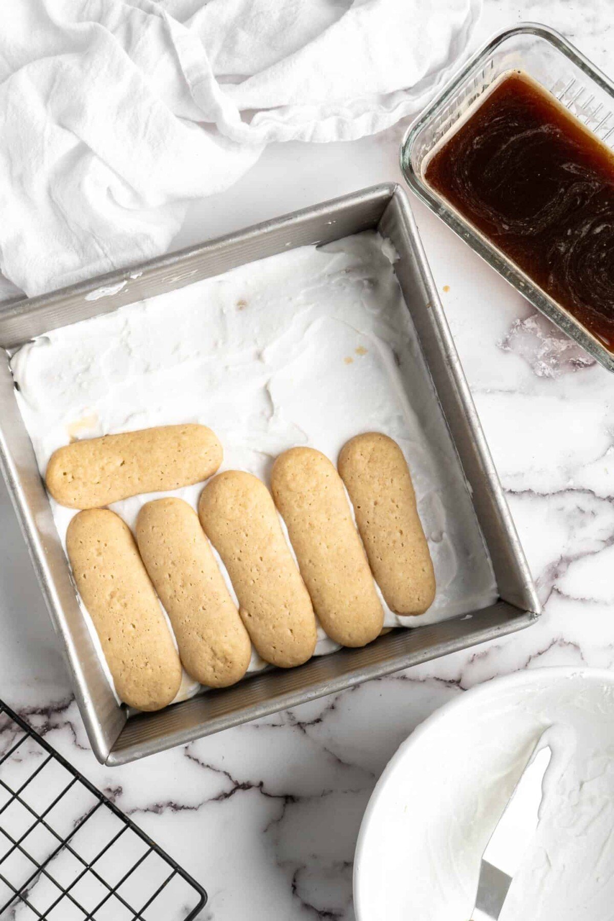 Six ladyfingers in a baking tray on top of a layer of mascarpone