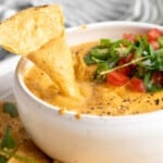 Dipping a tortilla chip into vegan queso