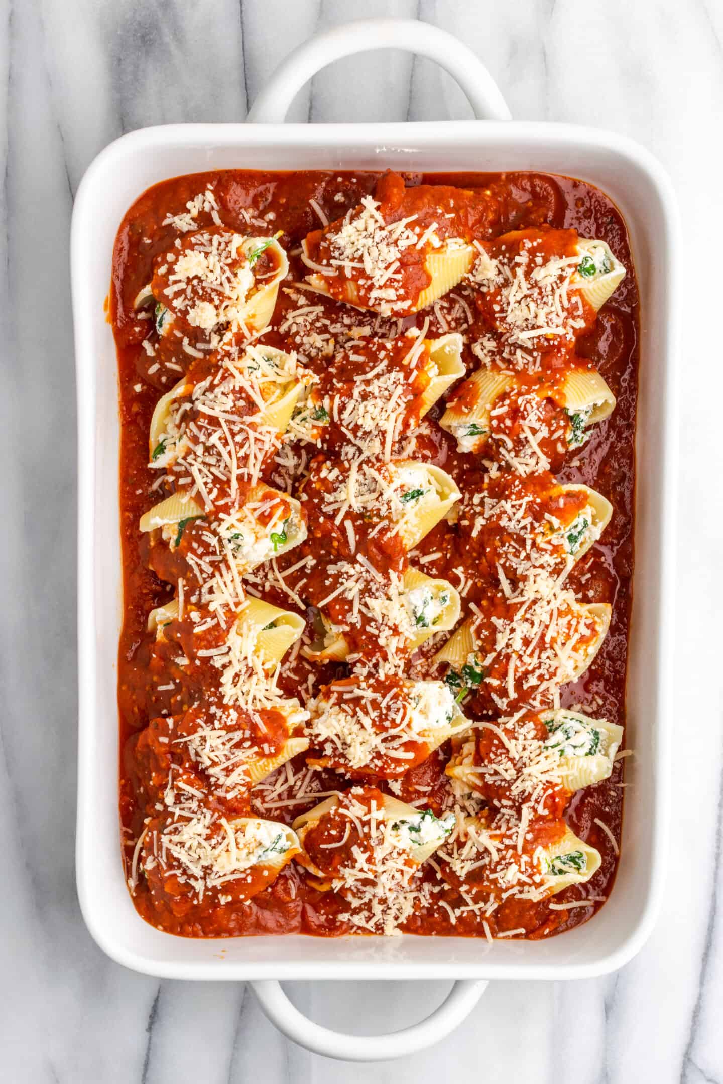Vegan stuffed shells in a casserole dish, covered in marinara sauce and cheese