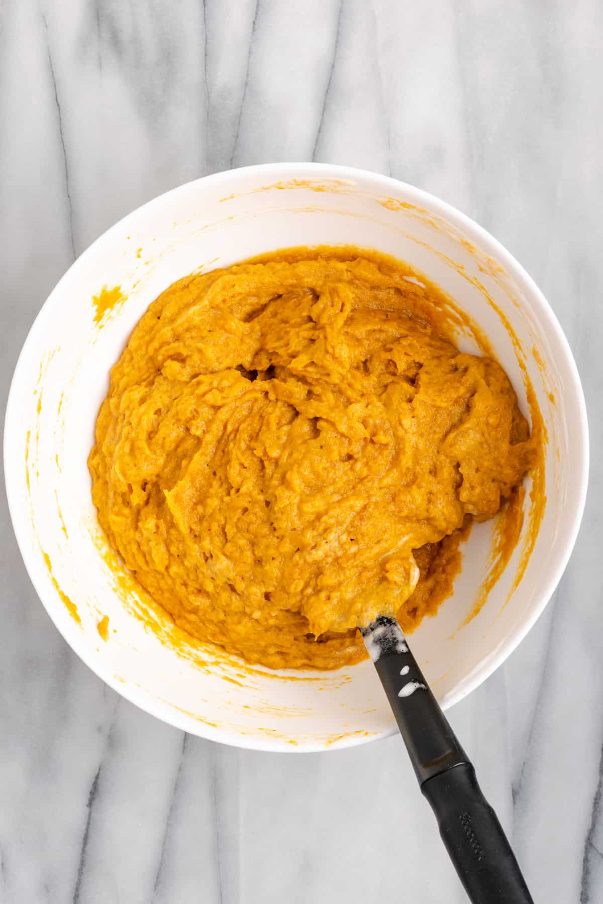 A mixing bowl with sweet potato soufflé batter in it, with a whisk in the bowl