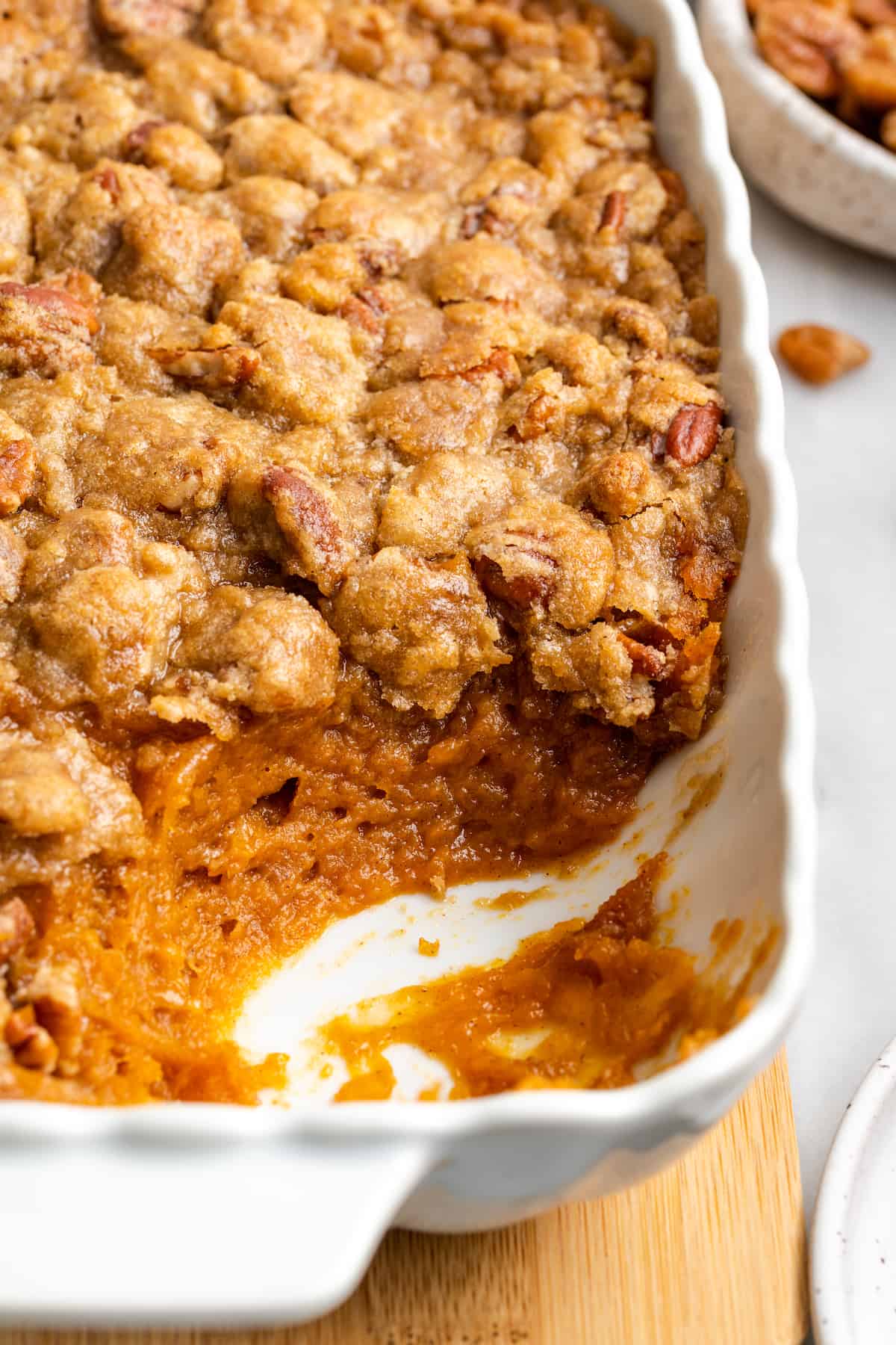A sweet potato soufflé in a casserole dish, with the corner piece missing