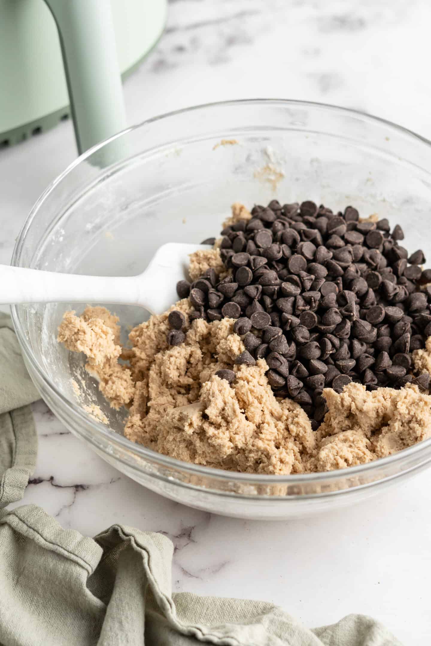 Cookie dough and chocolate chunks in glass bowl with spatula
