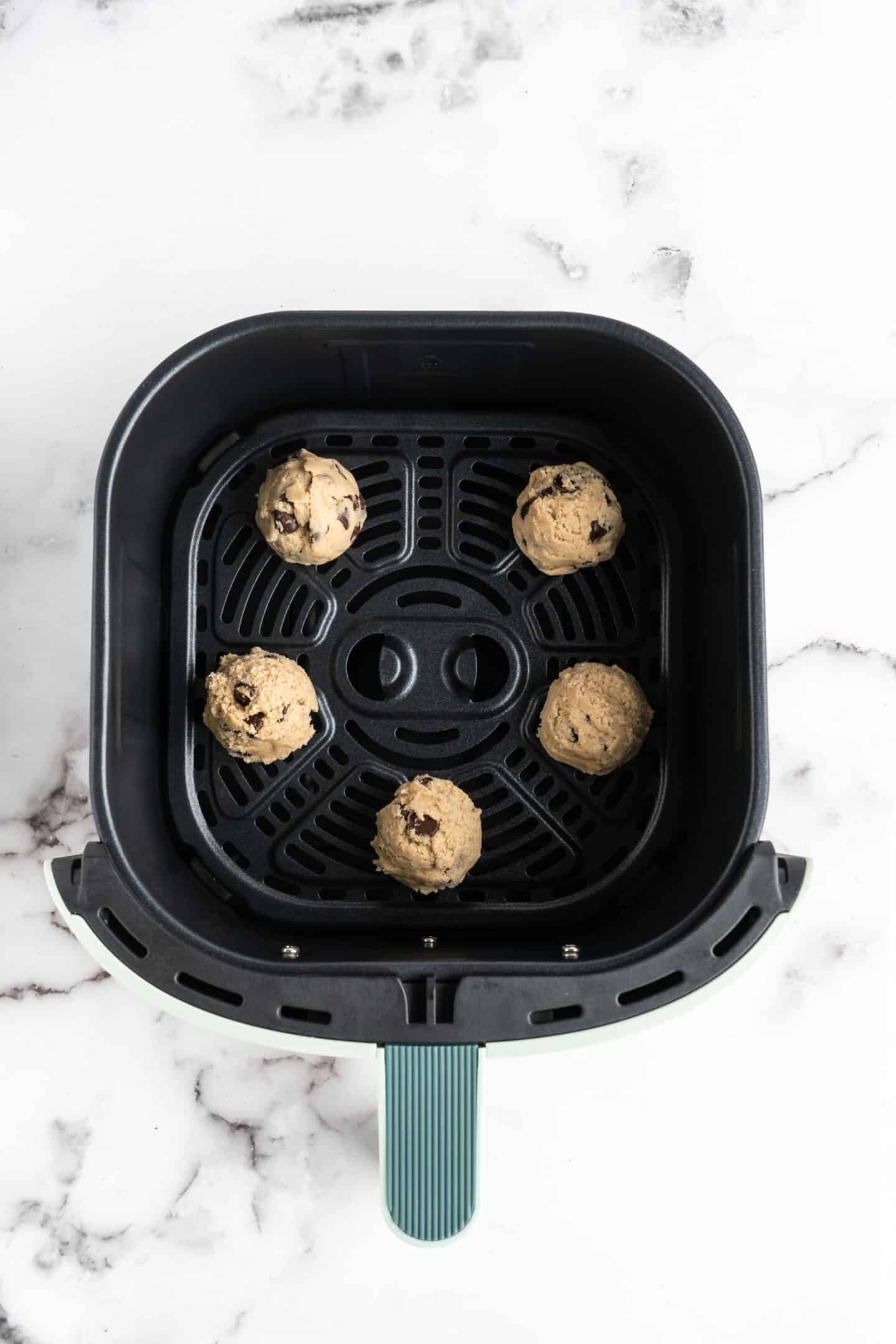 Balls of chocolate chip cookie dough in air fryer base