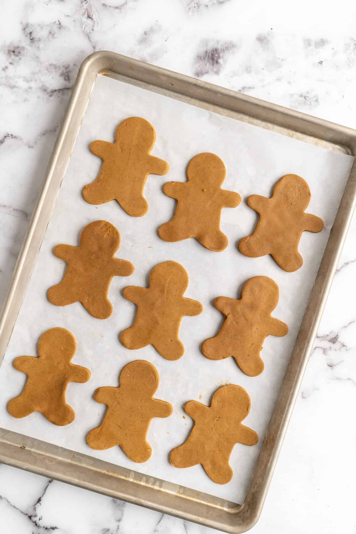 A baking sheet with nine unbaked gingerbread men on it