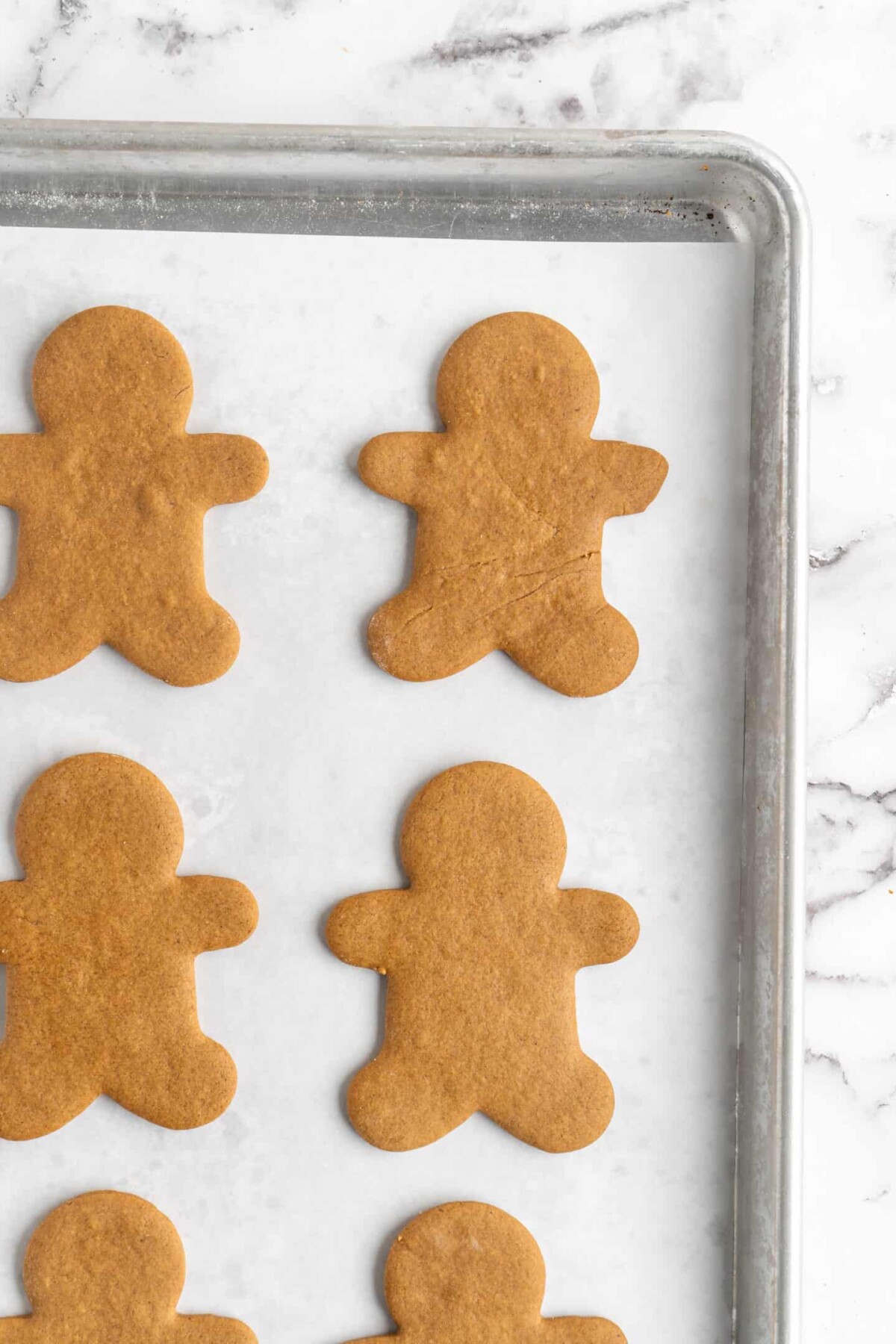 The corner of a baking sheet with cooked gingerbread men on it