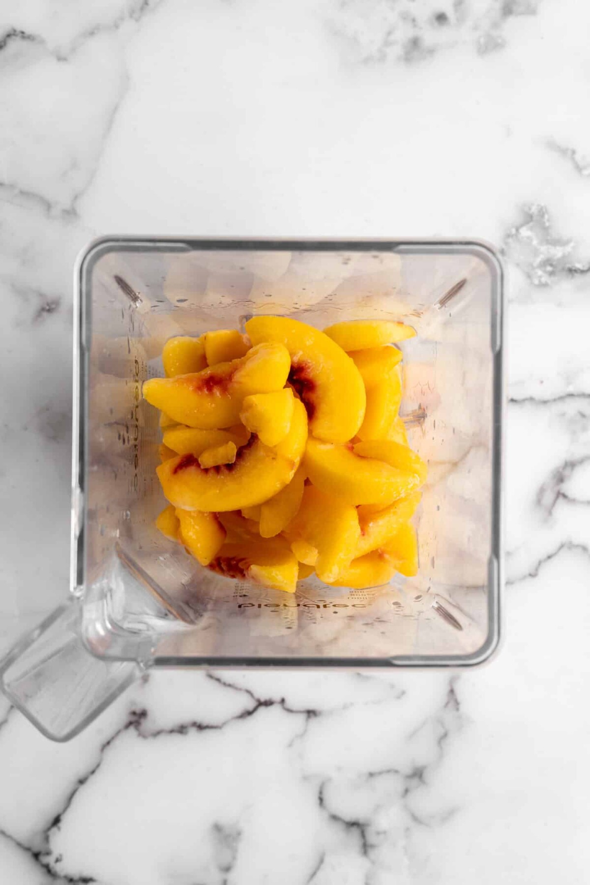 Overhead view of a blender filled with peach slices