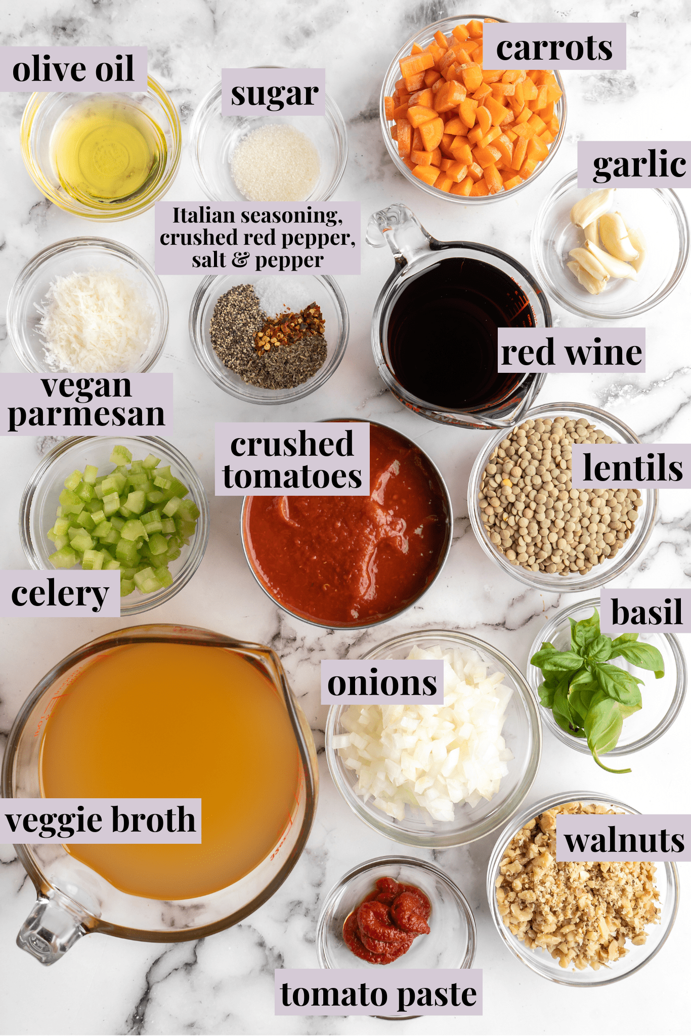 Labeled overhead view of a bowl the ingredients for walnut lentil bolognese: veggie broth, tomato paste, walnuts, basil, onions, lentils, crushed tomatoes, celery, red wine, vegan parmesan, garlic, carrots, sugar, and olive oil