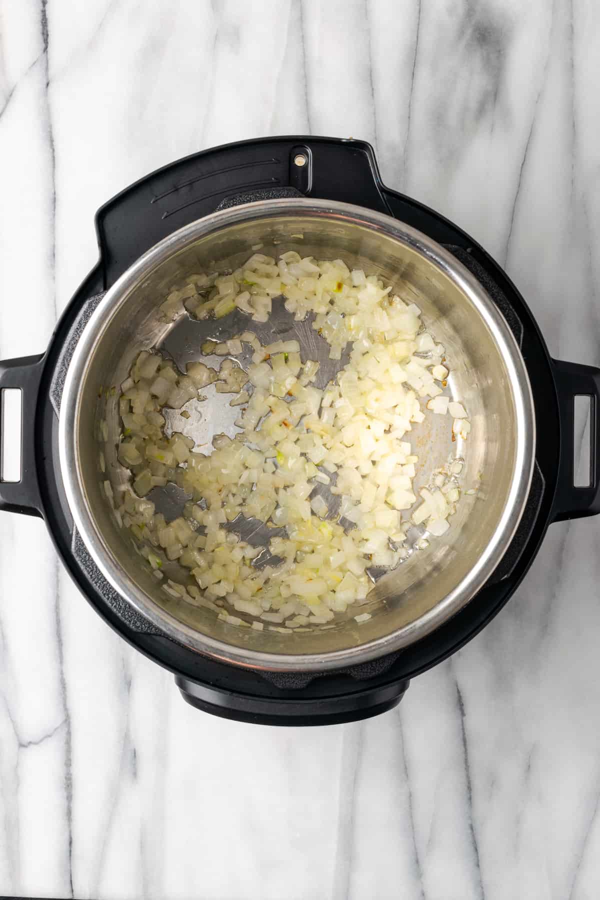 An Instant Pot with diced onions cooking in it