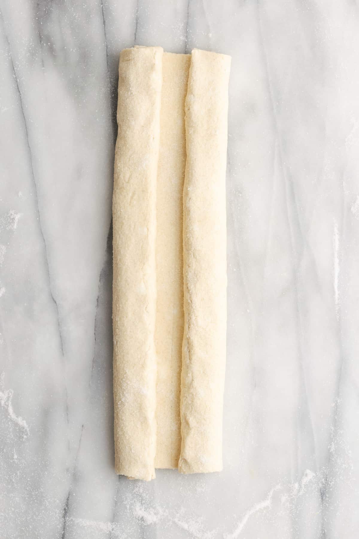 A rectangle of puff pastry dough with both sides folded in towards the middle