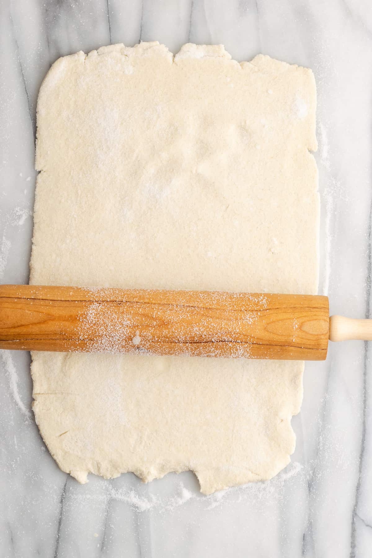 A rectangle of puff pastry with a rolling pin on it