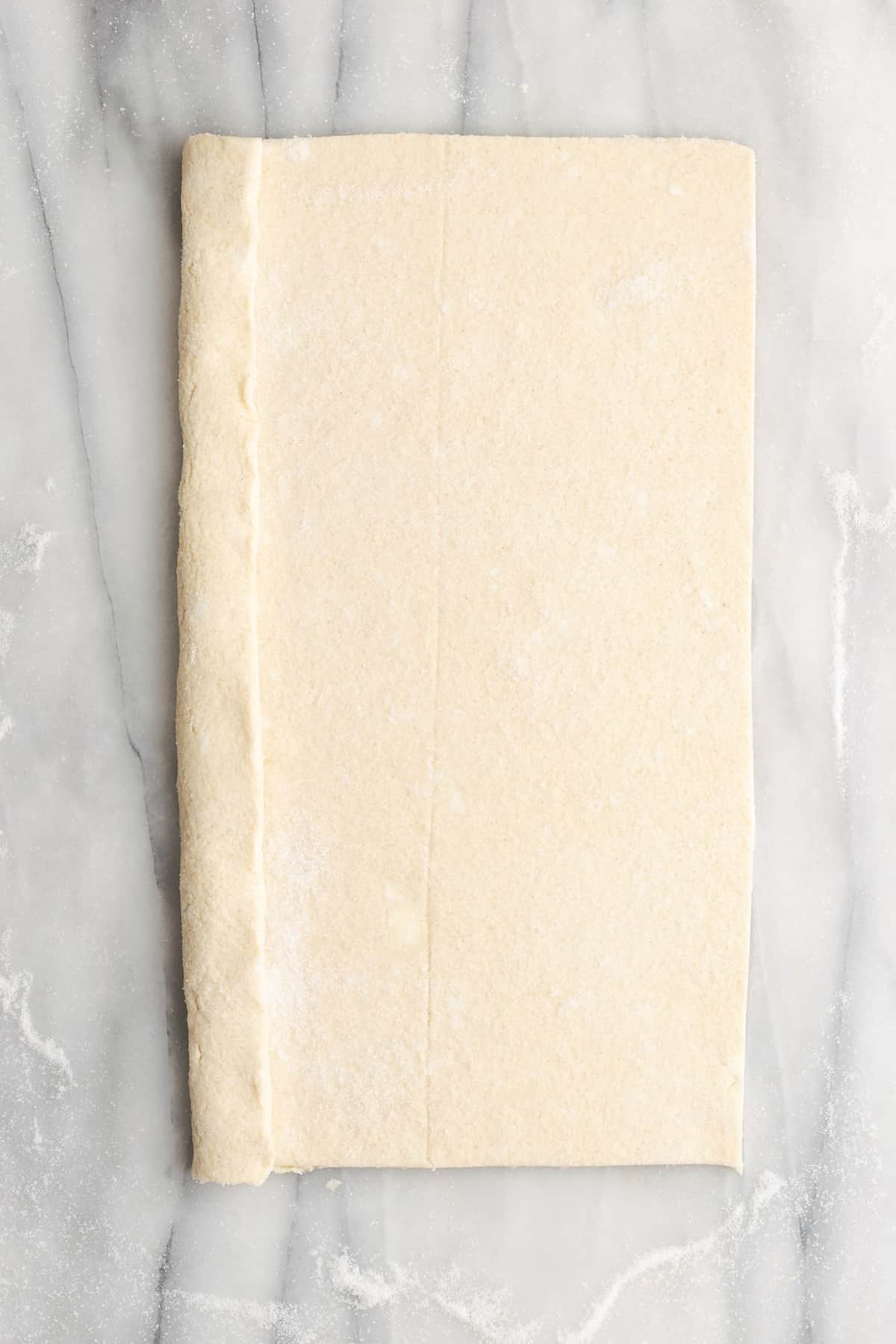 A rectangle of puff pastry dough with one side folded in about a quarter of the way