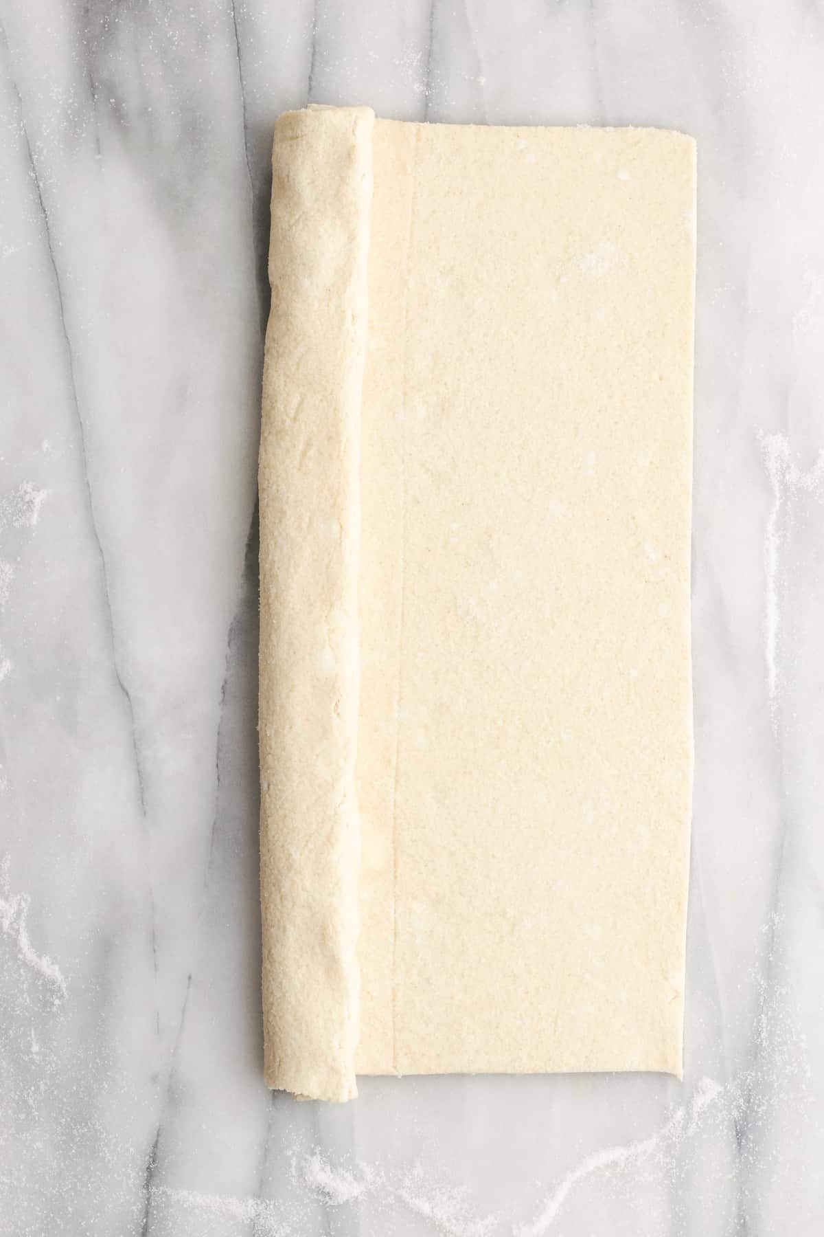 A rectangle of puff pastry with one side folded in towards the middle half way, and the other side not folded