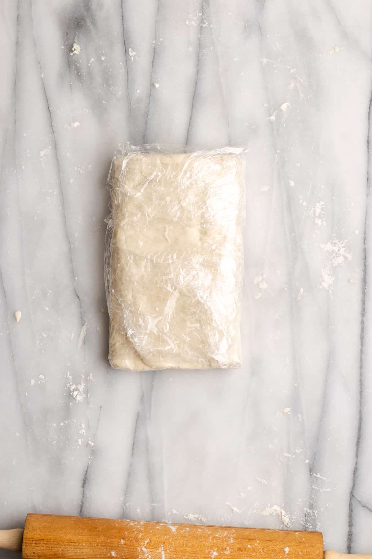 Puff pastry dough folded in an envelope, wrapped in plastic wrap
