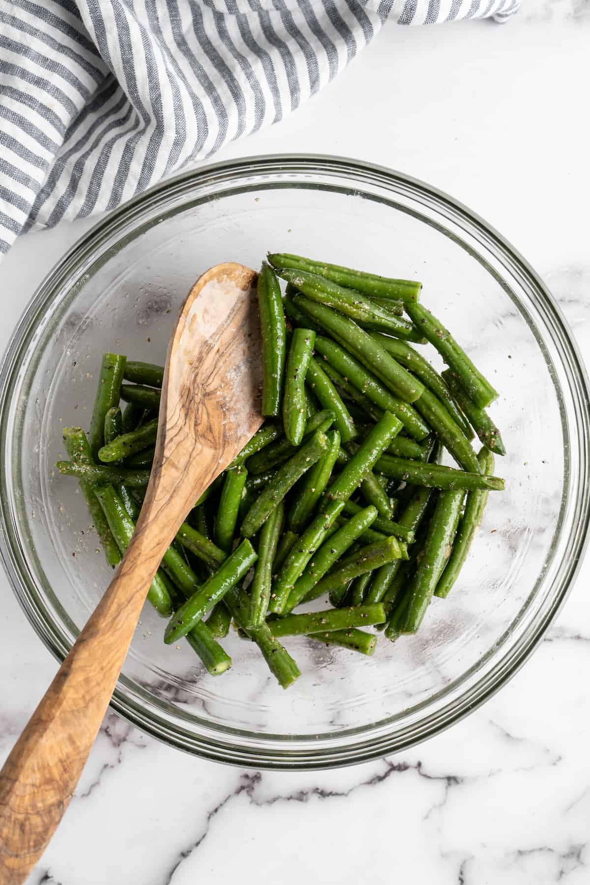 Green beans in glass bowl with wooden spoon