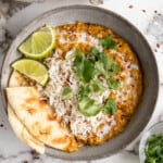 Bowl of red lentil curry with naan and rice