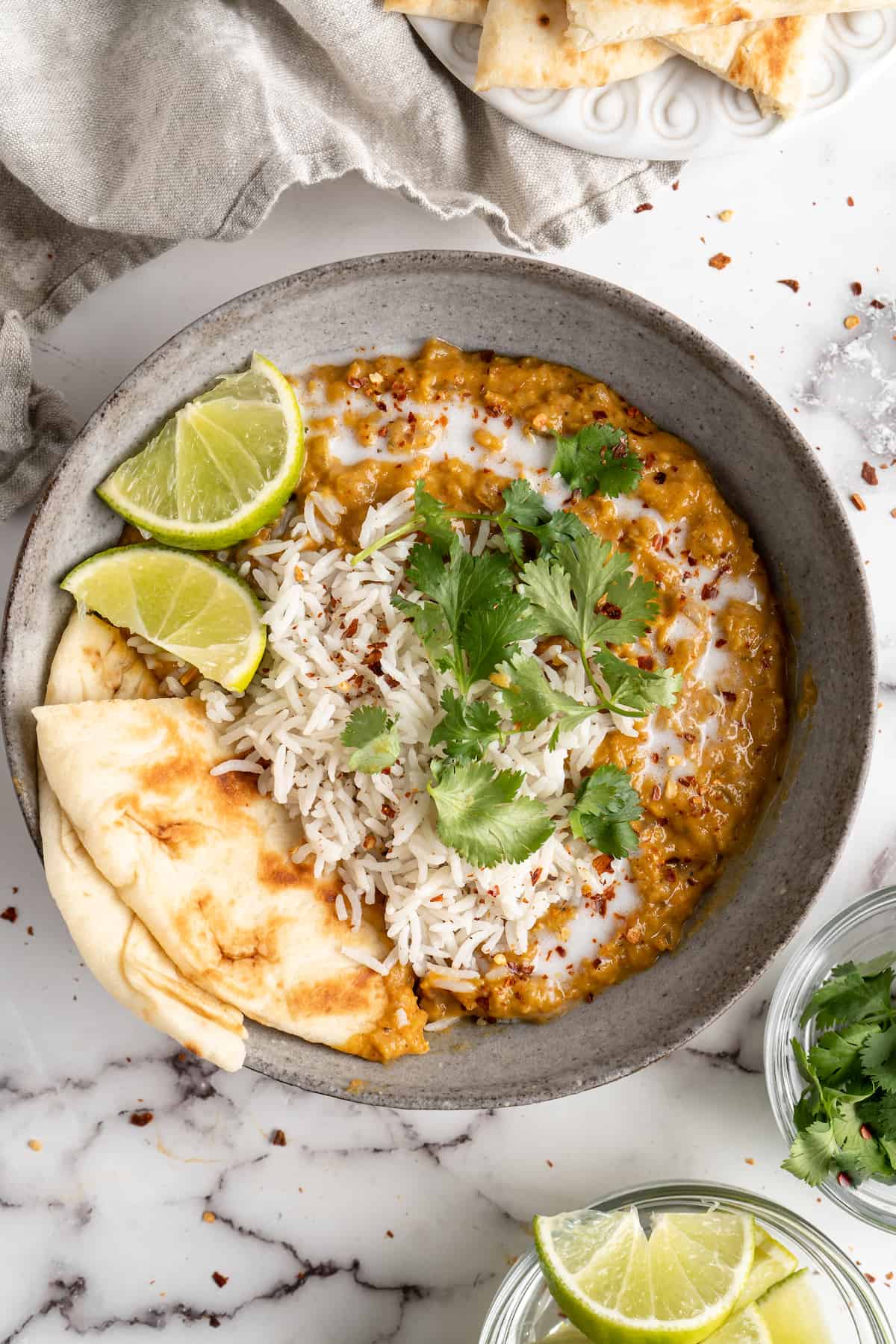 Bowl of red lentil curry with naan and rice
