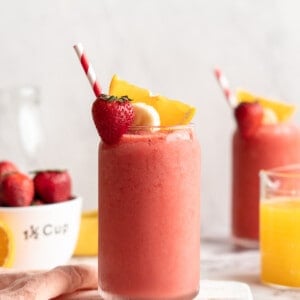 Strawberry banana smoothie in glass with straw and fresh fruit