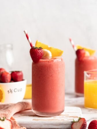 Strawberry banana smoothie in glass with straw and fresh fruit