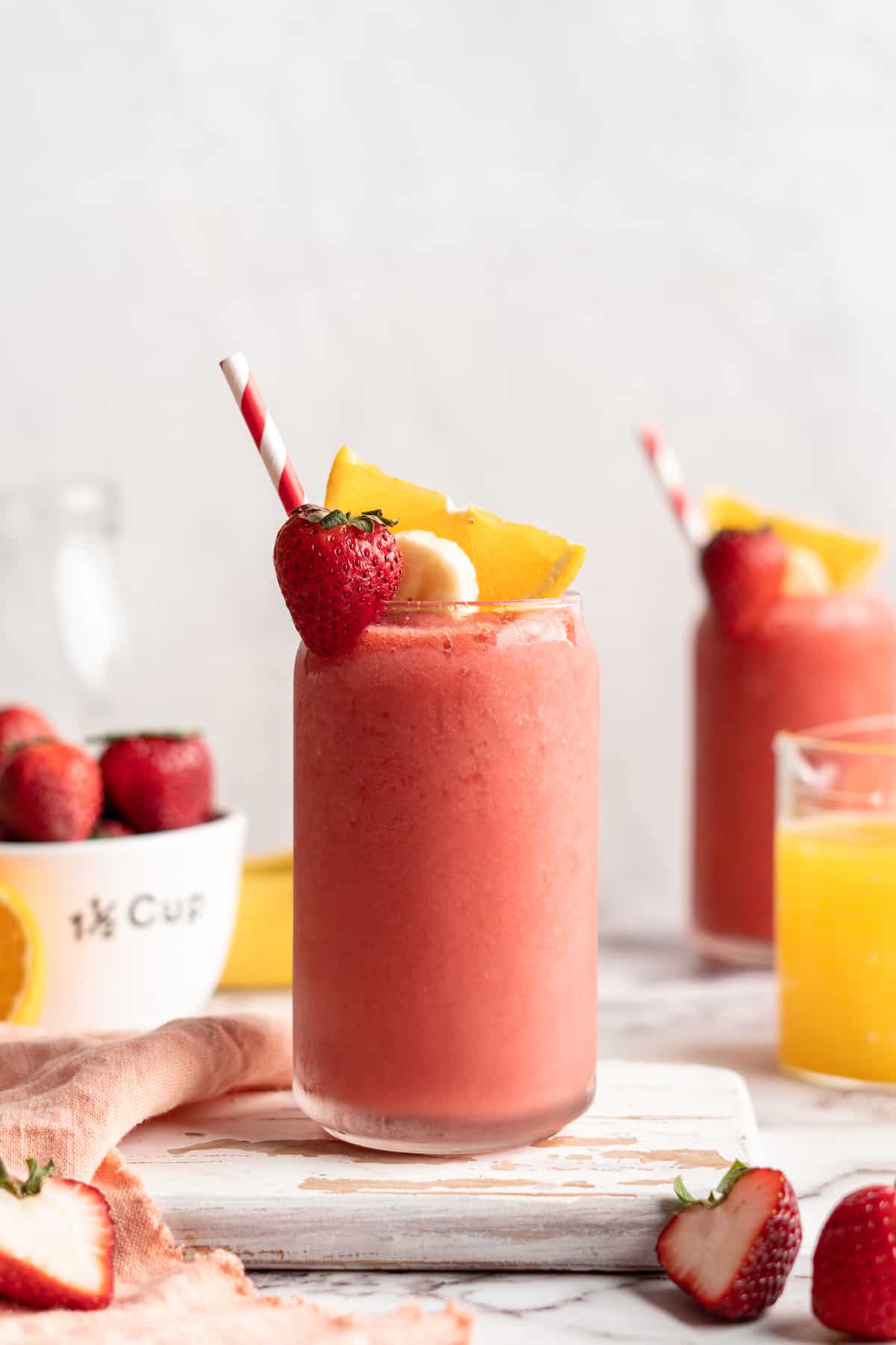 Strawberry banana smoothie in glass with straw and fresh fruit