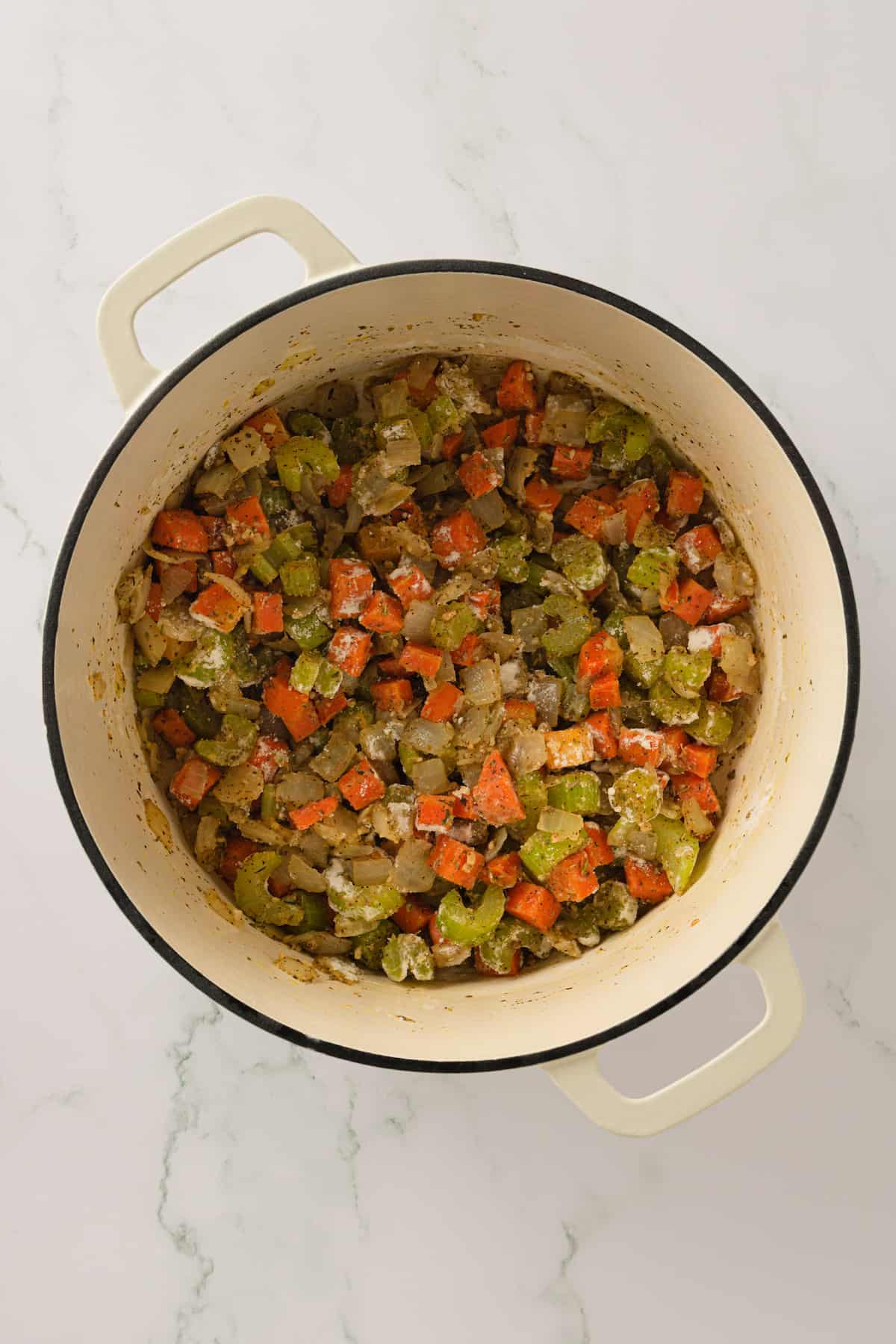 Overhead view of cooked vegetables and flour in Dutch oven