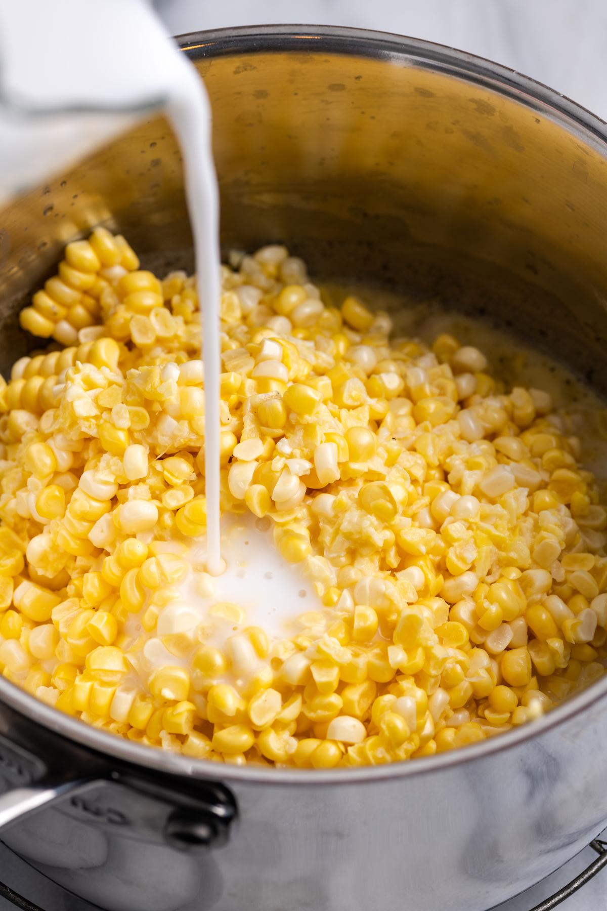 Pouring vegan milk into pot of corn