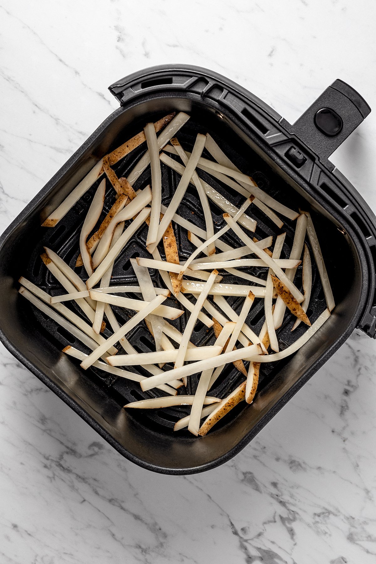 Overhead view of uncooked shoestring fries in air fryer