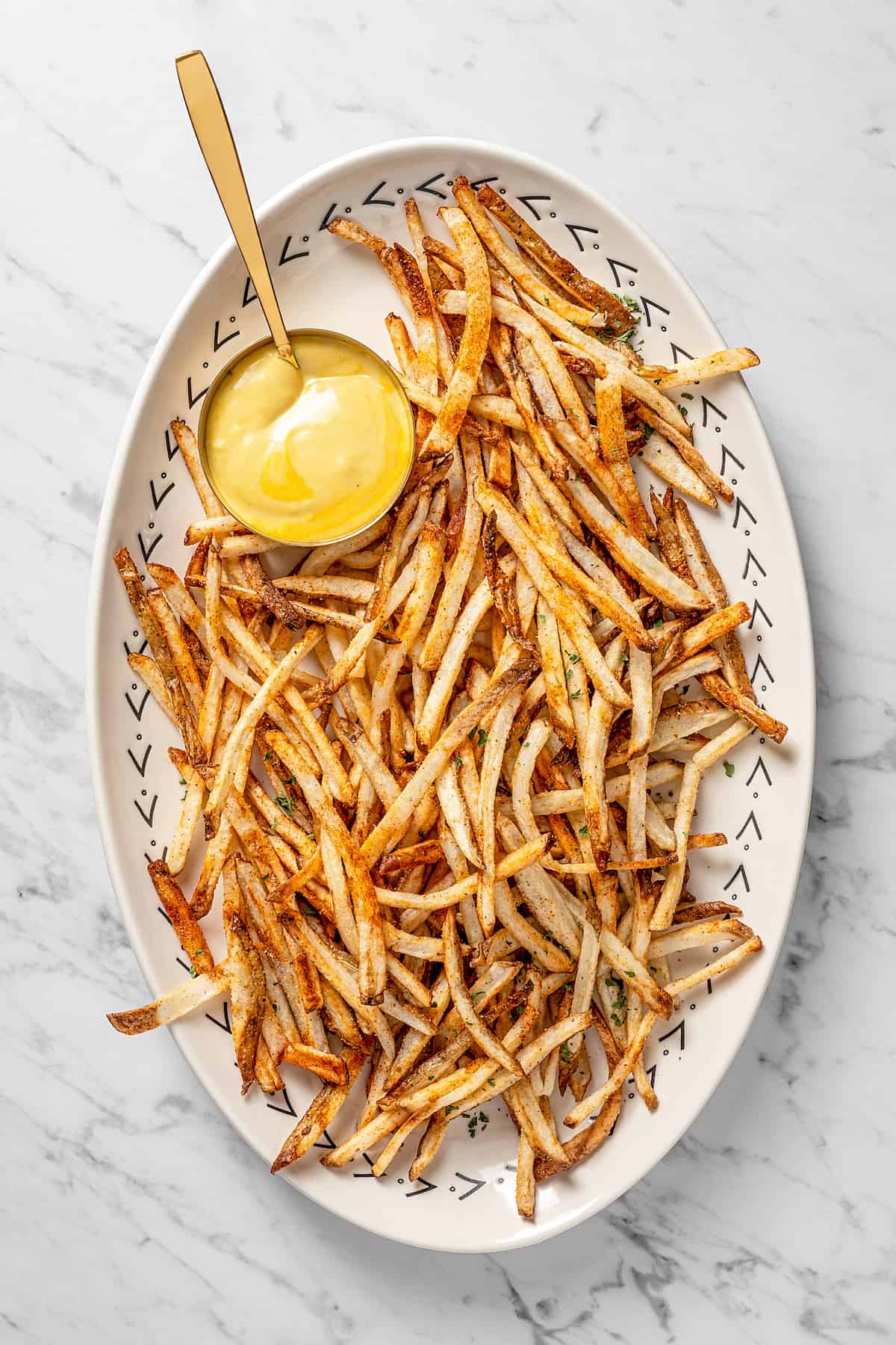 Overhead view of air fryer shoestring fries on platter with dipping sauce